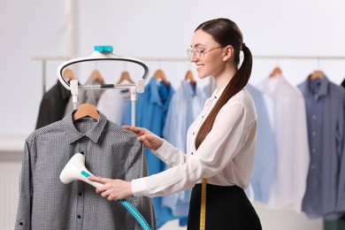 Woman steaming shirt on hanger in room