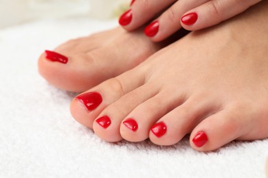 Photo of Woman with stylish red toenails after pedicure procedure on white terry towel, closeup