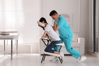 Photo of Woman receiving massage in modern chair indoors