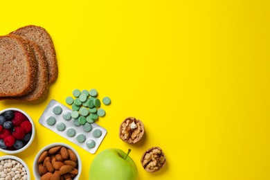 Food and prebiotic pills on yellow background, flat lay. Space for text