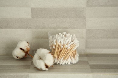 Photo of Cotton swabs and flowers on tiled surface indoors