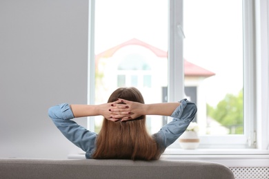 Young beautiful woman sitting near window at home