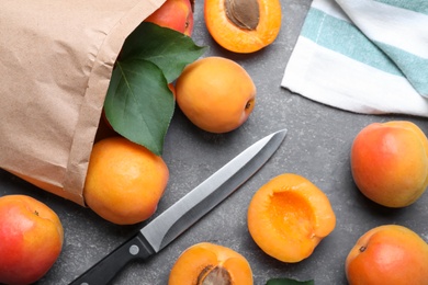 Photo of Many fresh ripe apricots and knife on grey table, flat lay