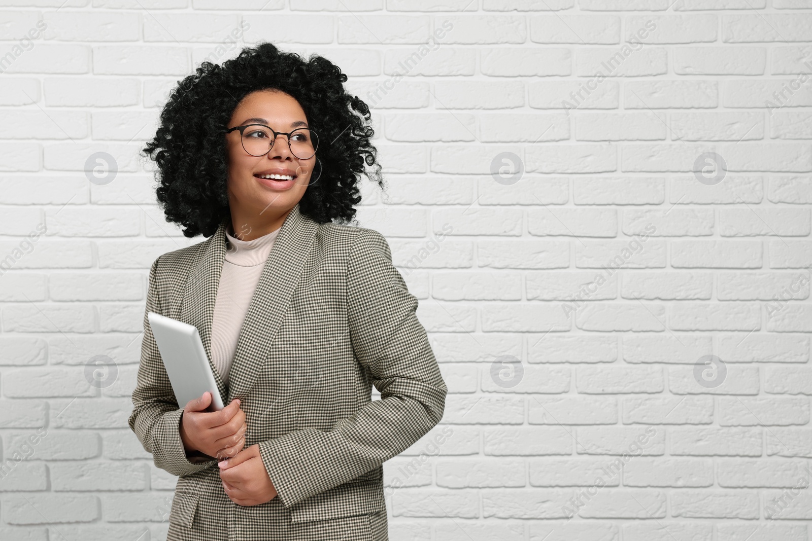 Photo of Young businesswoman with tablet near white brick wall. Space for text