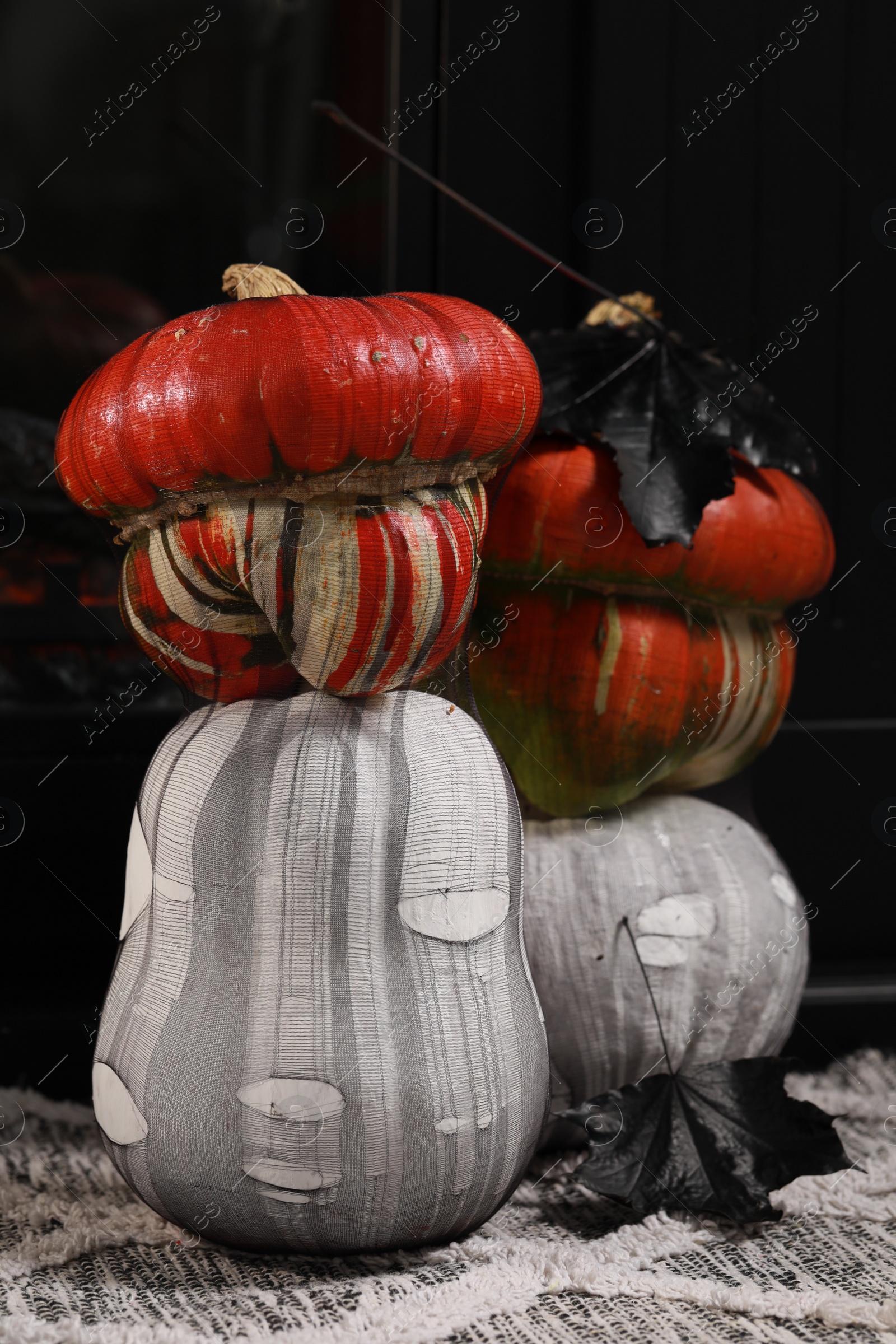 Photo of Colorful pumpkins on rug near fireplace. Halloween decorations