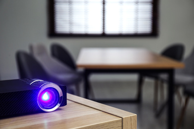 Photo of Modern video projector on wooden table in conference room. Space for text