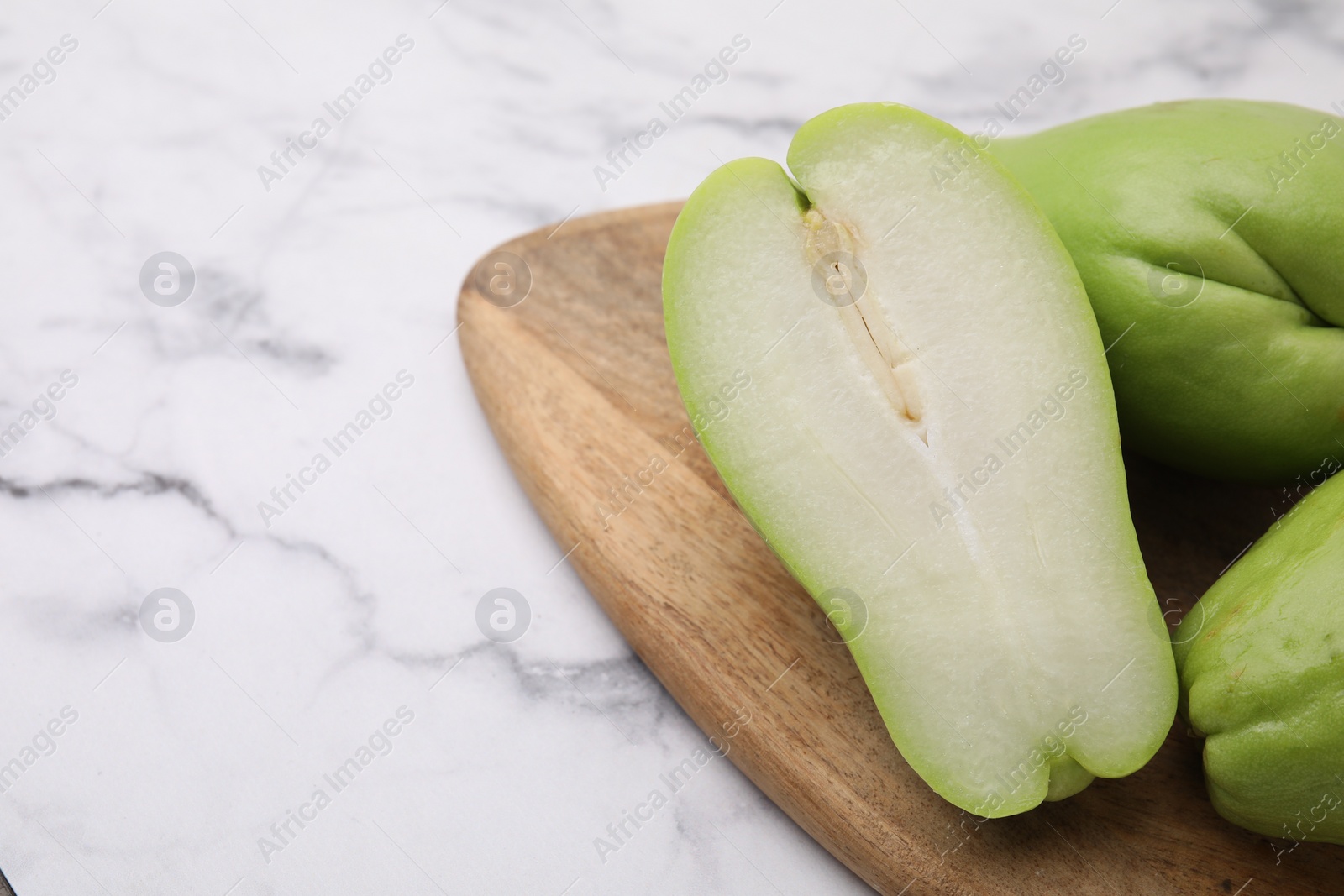 Photo of Fresh green chayote on light marble table, closeup. Space for text