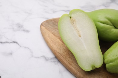 Fresh green chayote on light marble table, closeup. Space for text