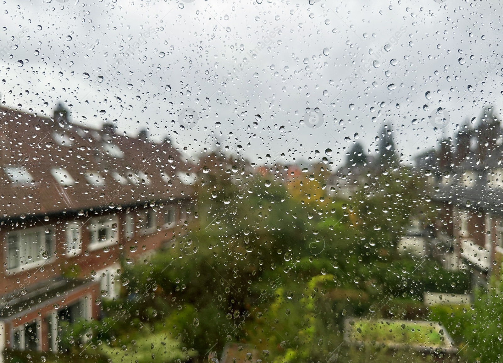 Photo of View on city street through window with water droplets on rainy day, closeup