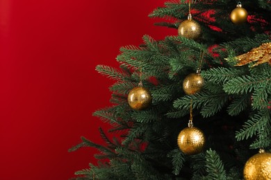 Photo of Beautifully decorated Christmas tree on red background, closeup. Space for text