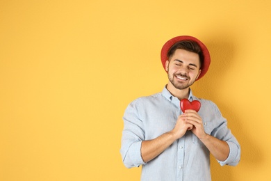 Man holding decorative heart on color background, space for text