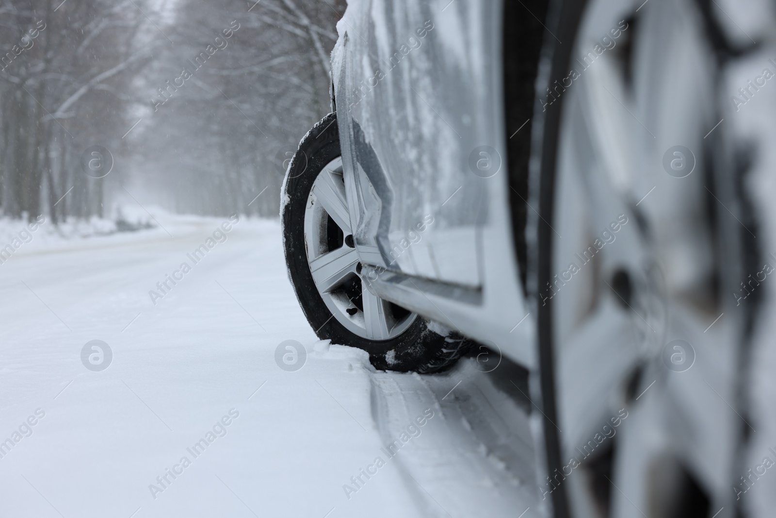 Photo of Car with winter tires on snowy road outdoors, closeup. Space for text