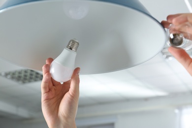 Man changing light bulb in pendant lamp indoors, closeup