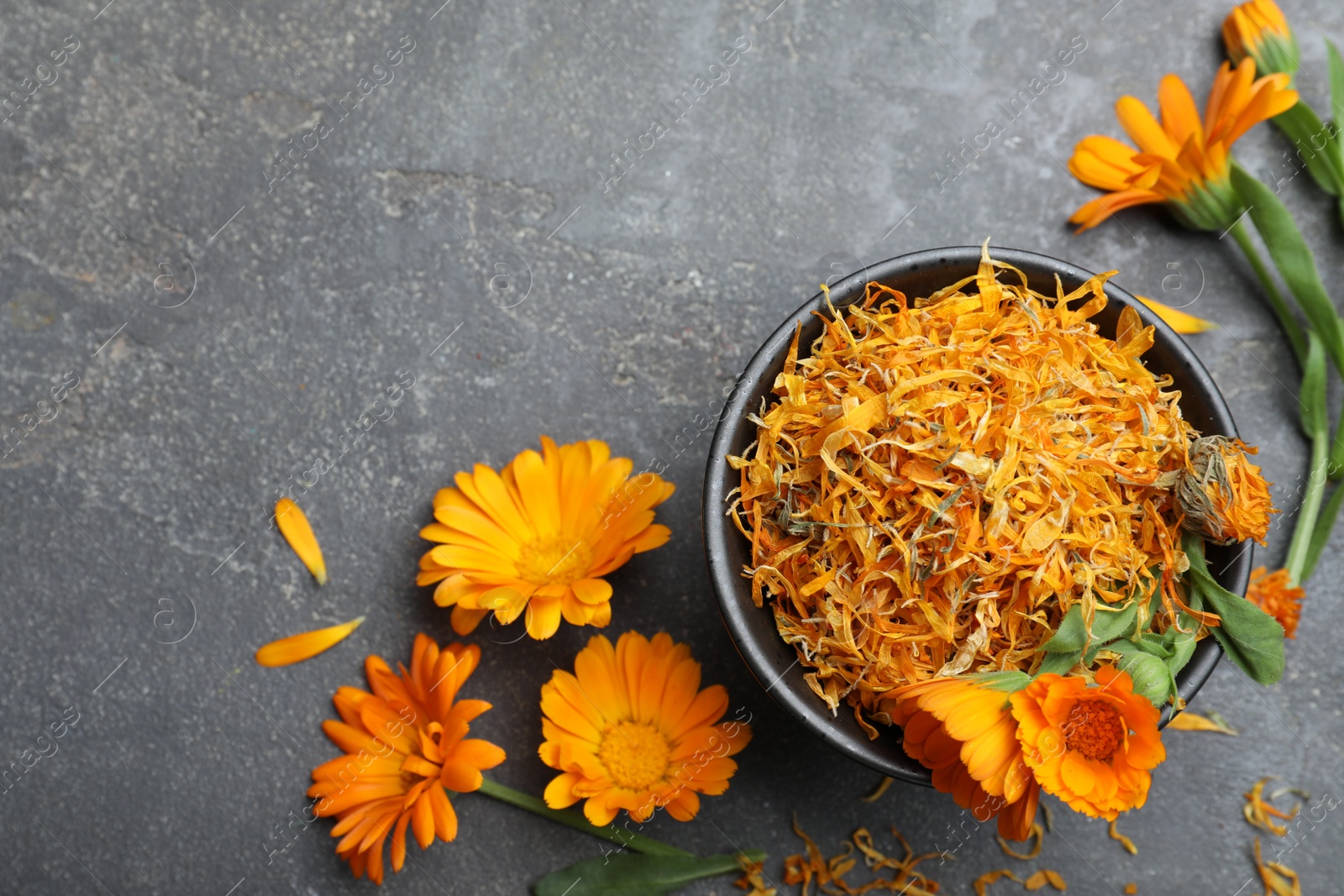 Photo of Dry and fresh calendula flowers on grey table, flat lay. Space for text