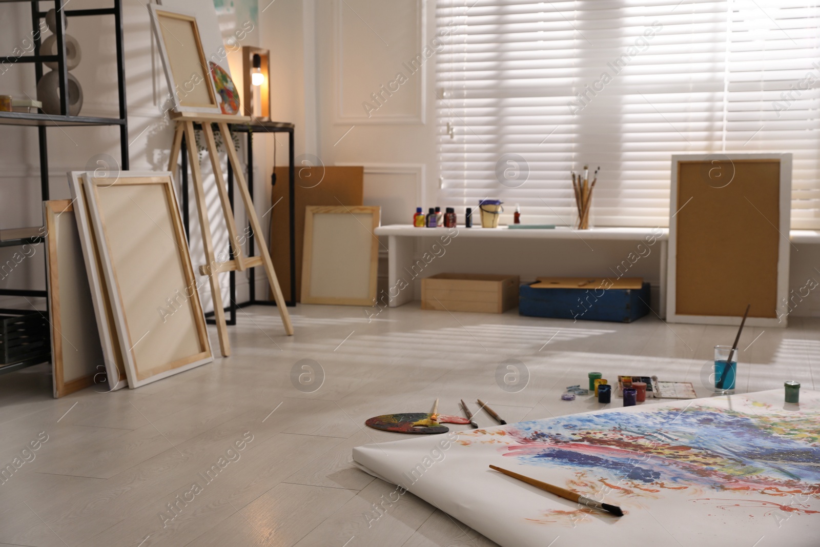 Photo of Wooden easel and abstract picture in art studio