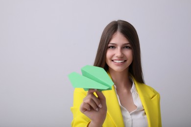 Photo of Beautiful teenage girl with paper plane on grey background. Space for text