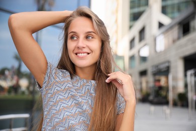 Photo of Portrait of beautiful young woman near building outdoors, space for text