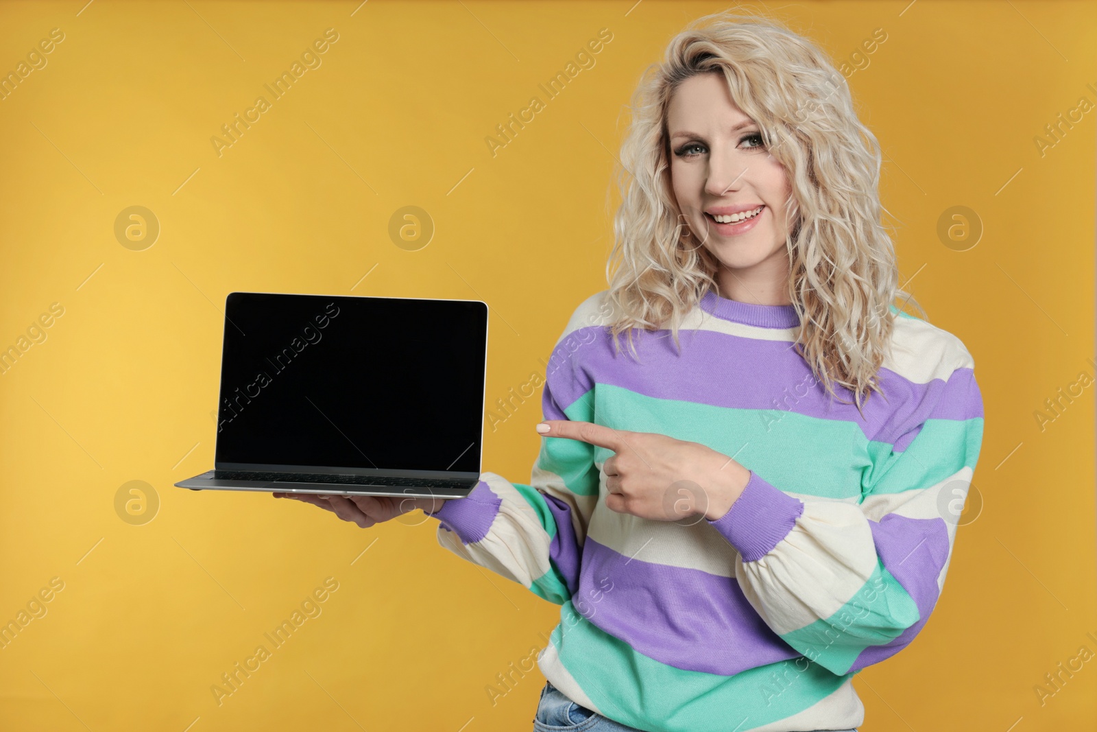 Photo of Beautiful young woman with laptop on orange background. Space for text