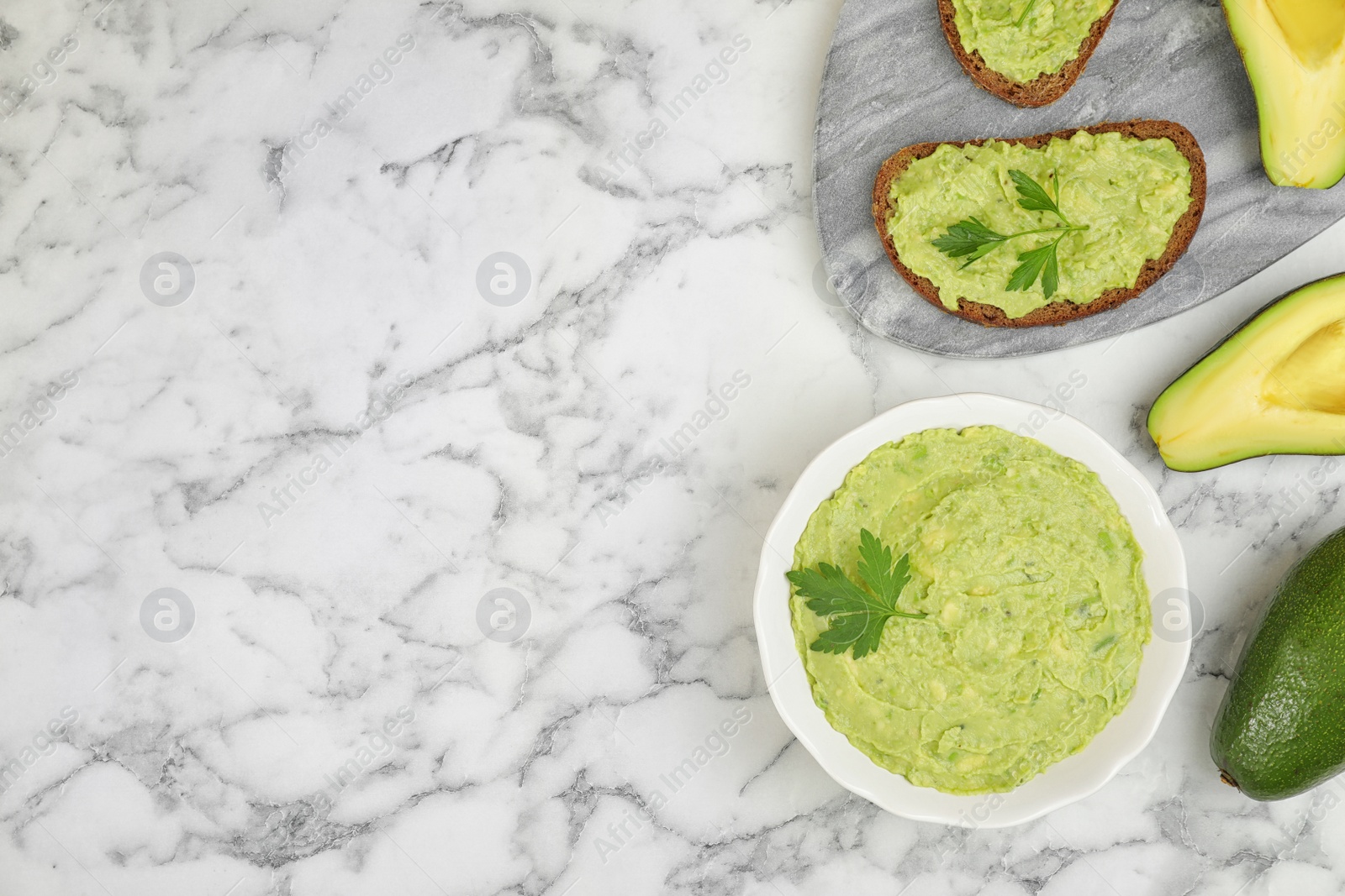 Photo of Flat lay composition with guacamole, sandwiches and avocados on white marble table. Space for text