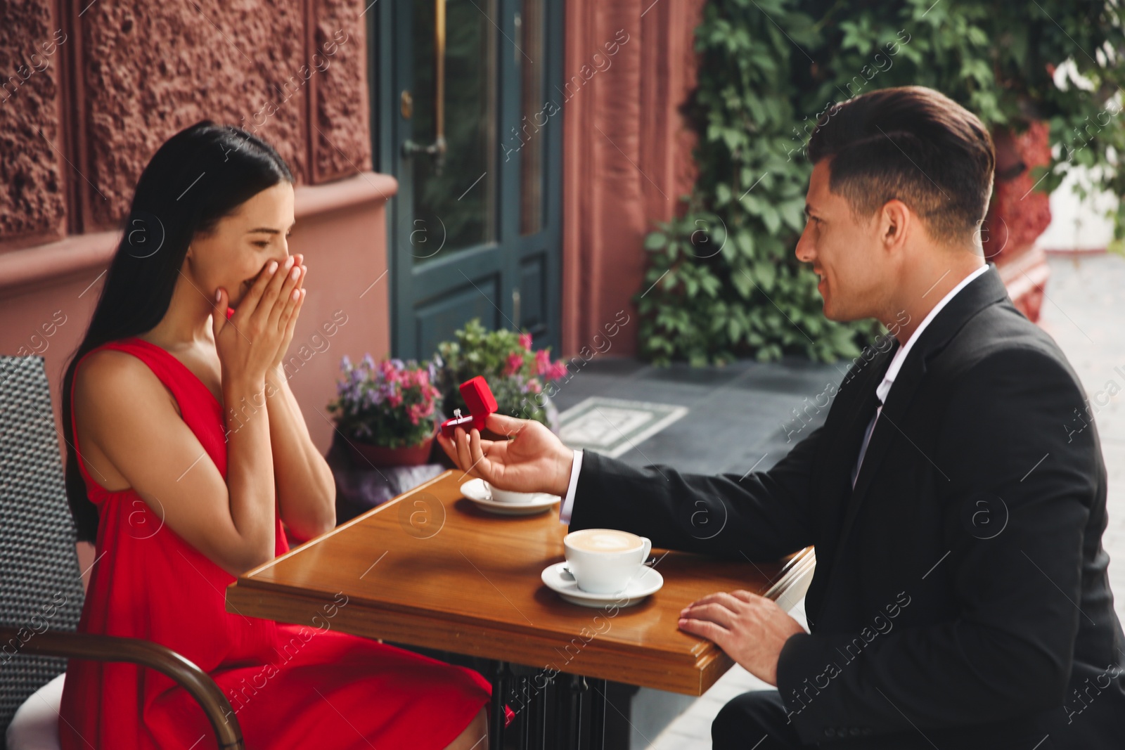 Photo of Man with engagement ring making proposal to his girlfriend in outdoor cafe