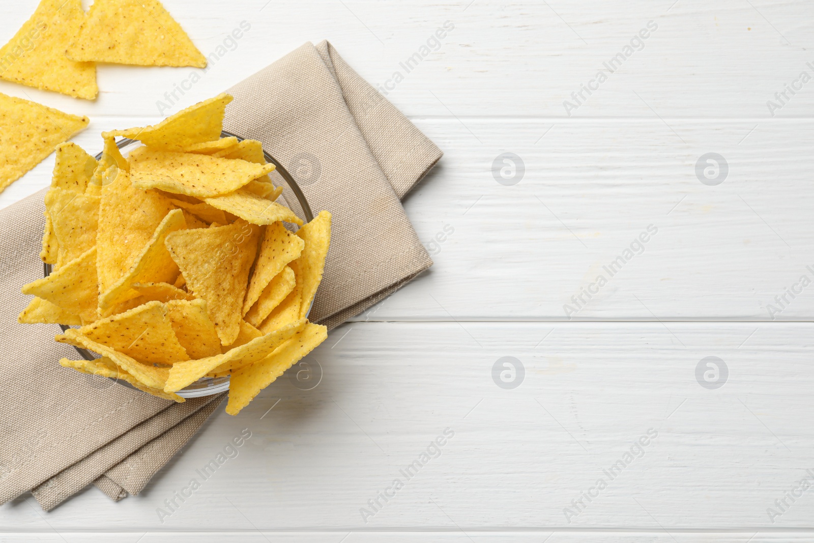 Photo of Tortilla chips (nachos) on white wooden table, flat lay. Space for text