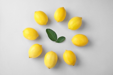 Tasty fresh lemons and leaves on white background, flat lay
