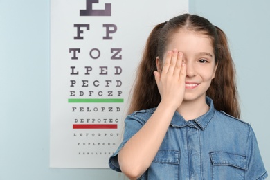 Cute little girl covering eye in ophthalmologist office
