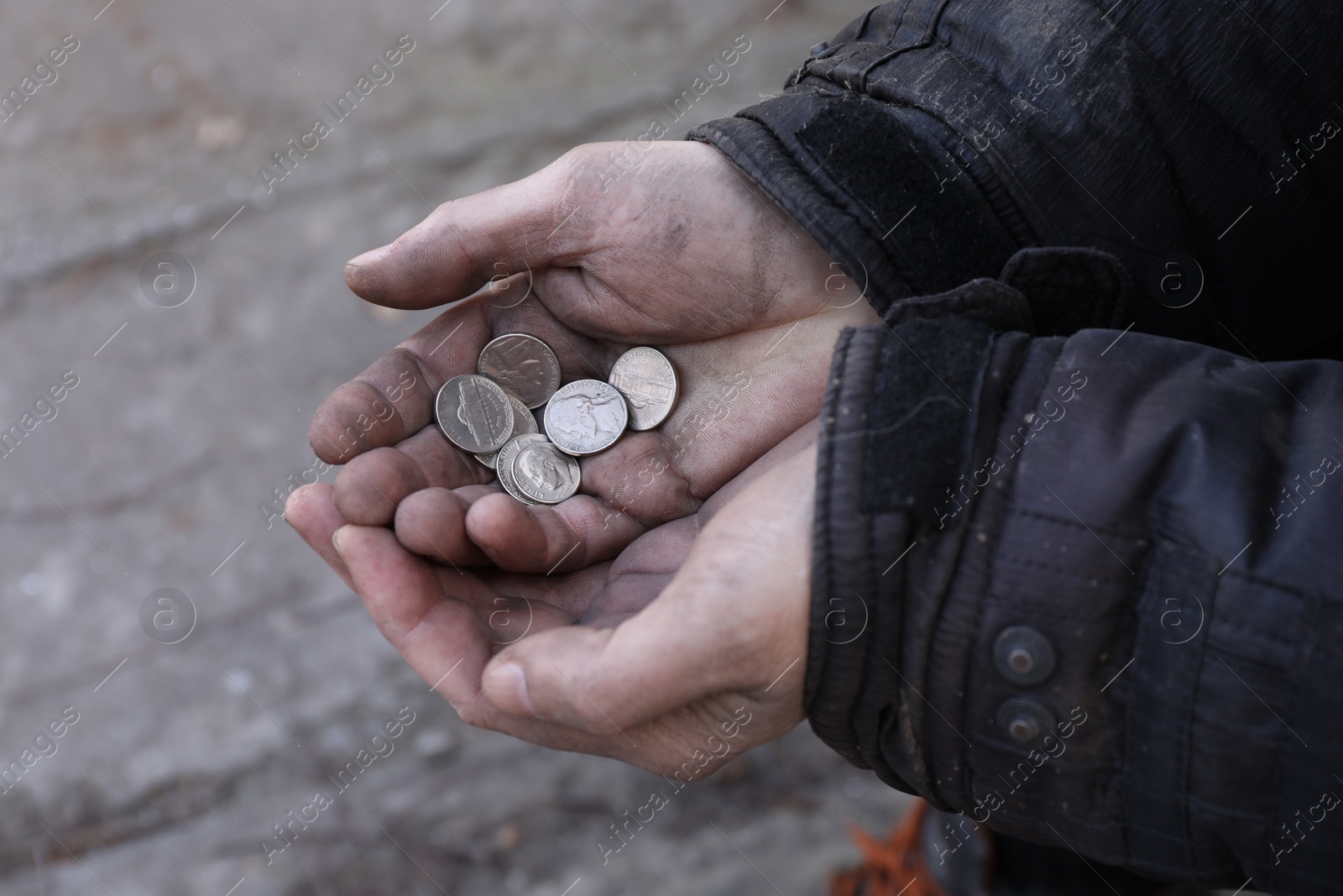 Photo of Poor homeless man holding coins outdoors, closeup