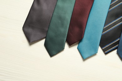 Photo of Different neckties on white wooden table, flat lay. Space for text