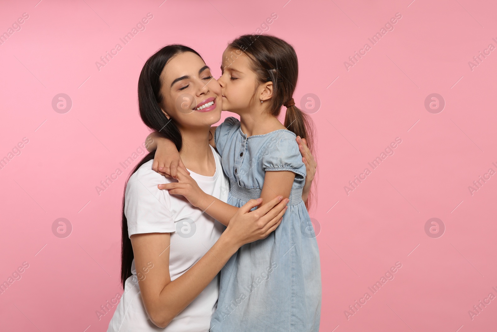Photo of Happy woman with her cute daughter on pink background. Mother's day celebration