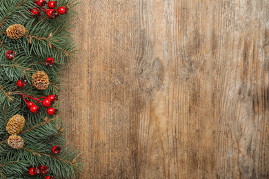 Photo of Flat lay composition with fir branches and berries on wooden background, space for text. Winter holidays