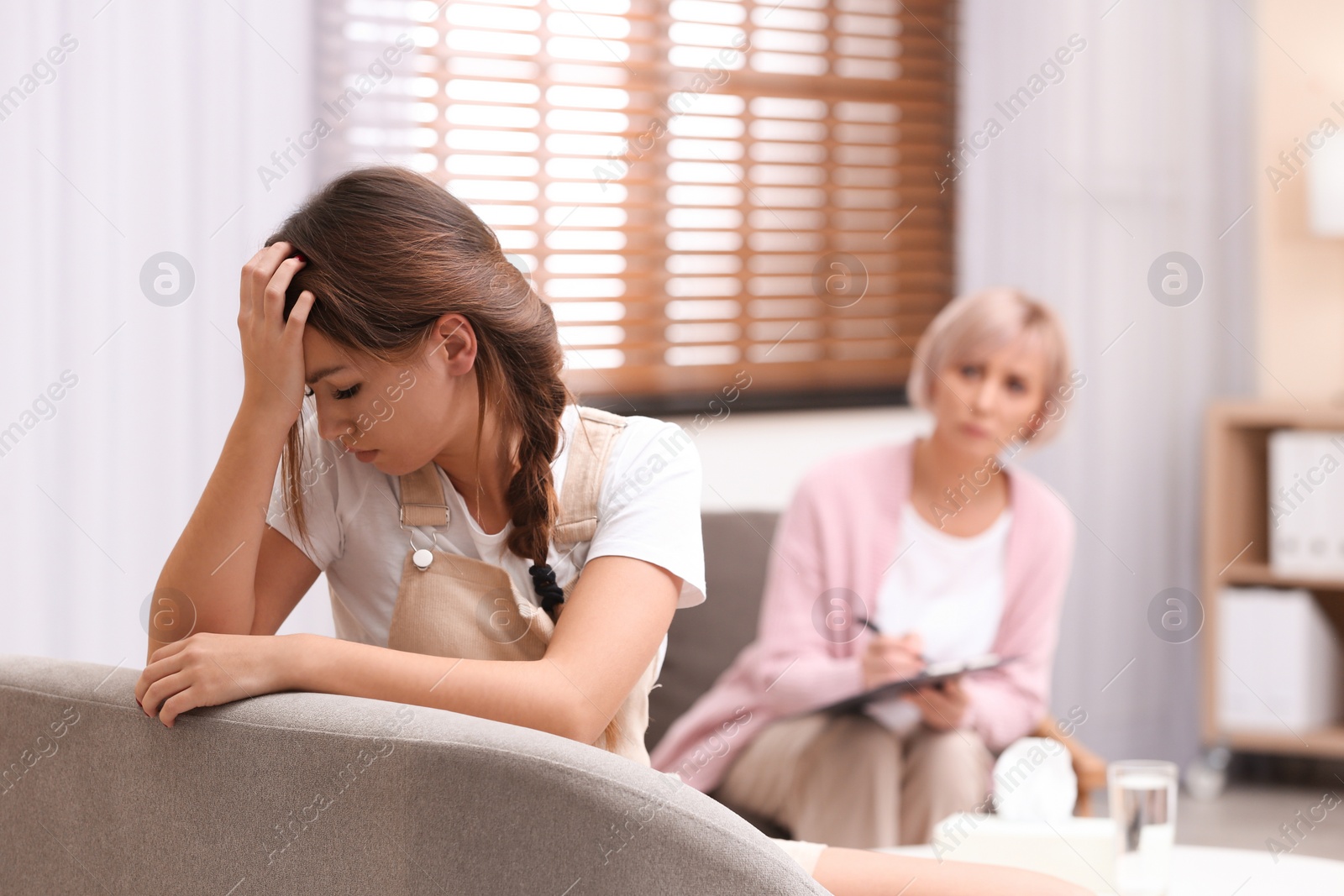 Photo of Psychotherapist working with teenage girl in office