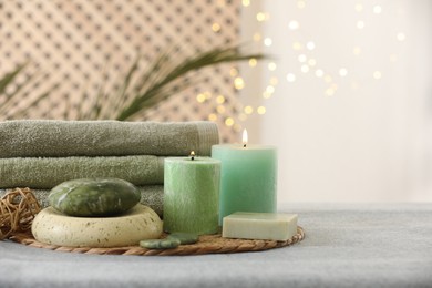 Spa composition. Burning candles, stones, soap and towels on soft grey surface, space for text