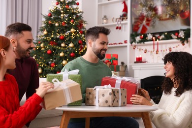 Photo of Happy friends exchanging Christmas gifts at home