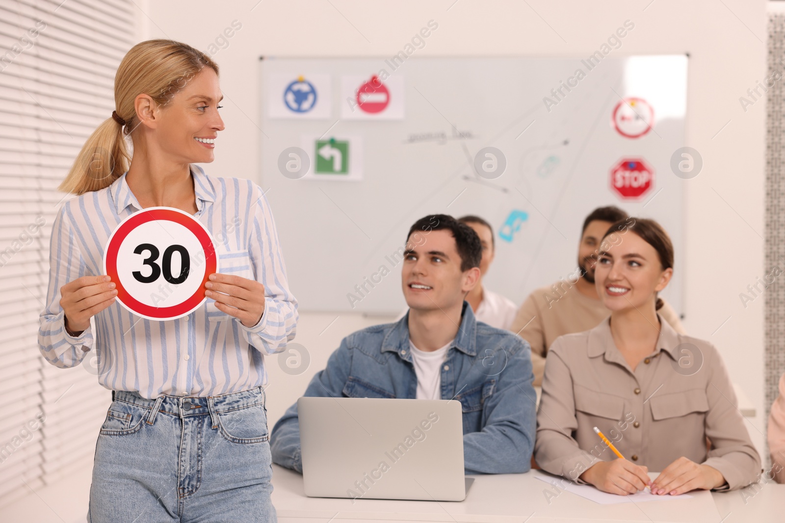 Photo of Teacher showing Speed Limit road sign during lesson in driving school