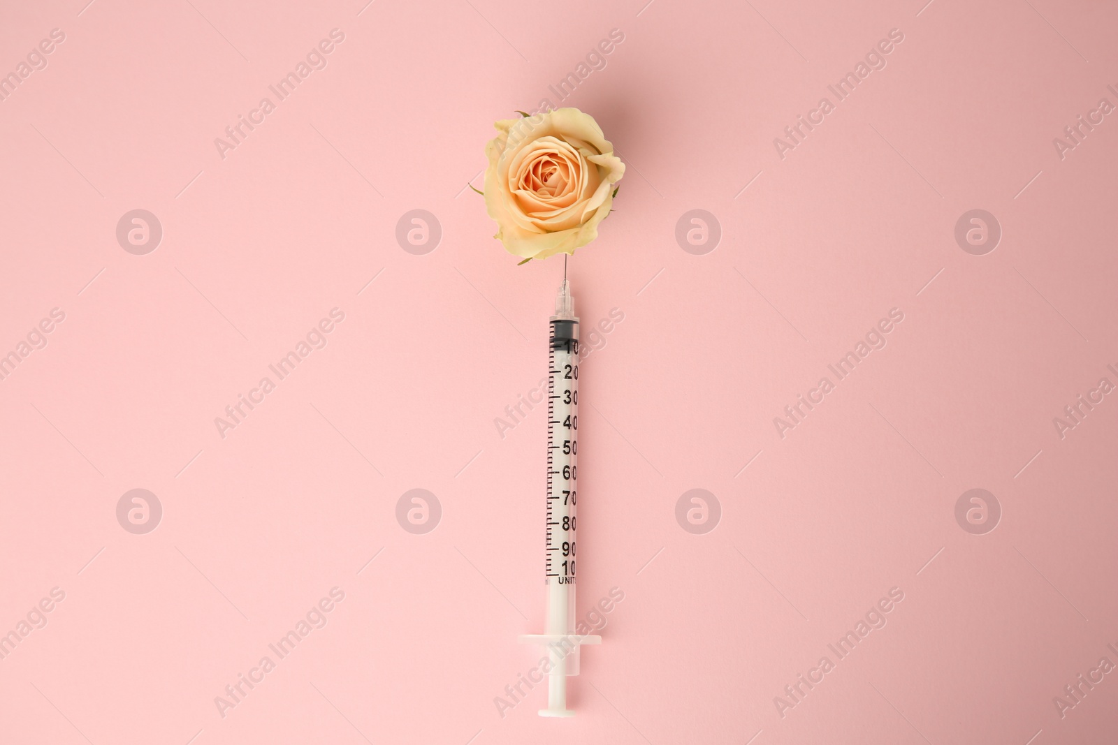 Photo of Medical syringe and beautiful rose on light pink background, top view