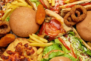 French fries, pizza and other fast food as background, top view
