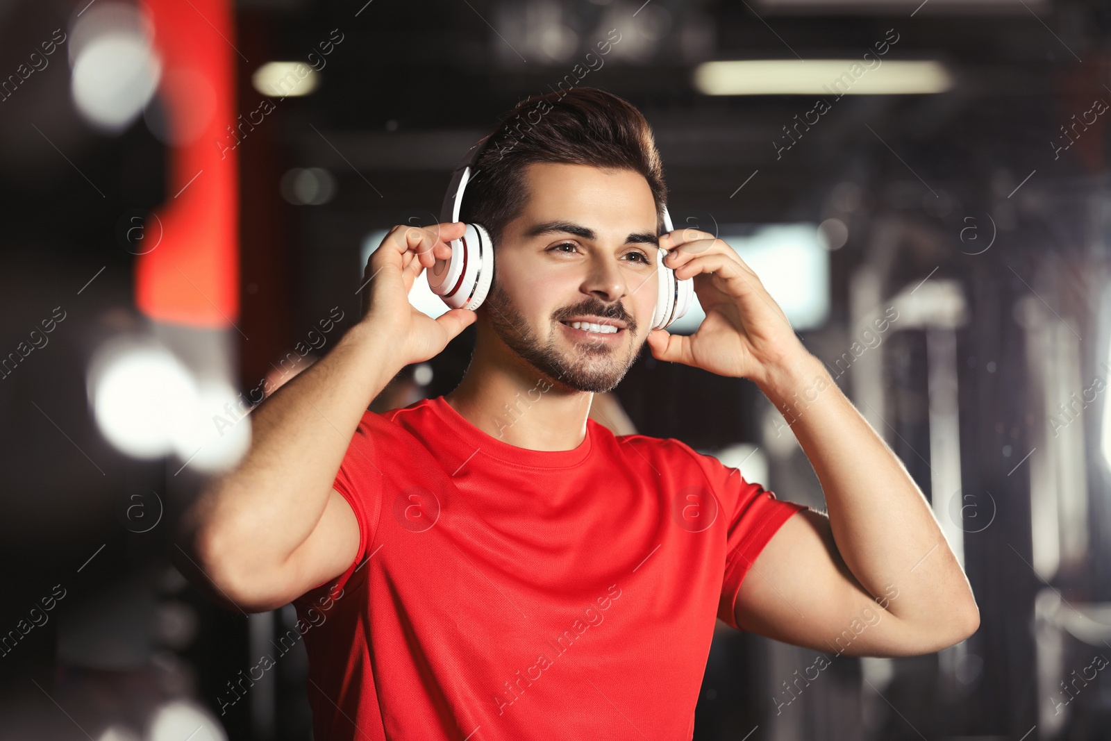 Photo of Young man listening to music with headphones at gym