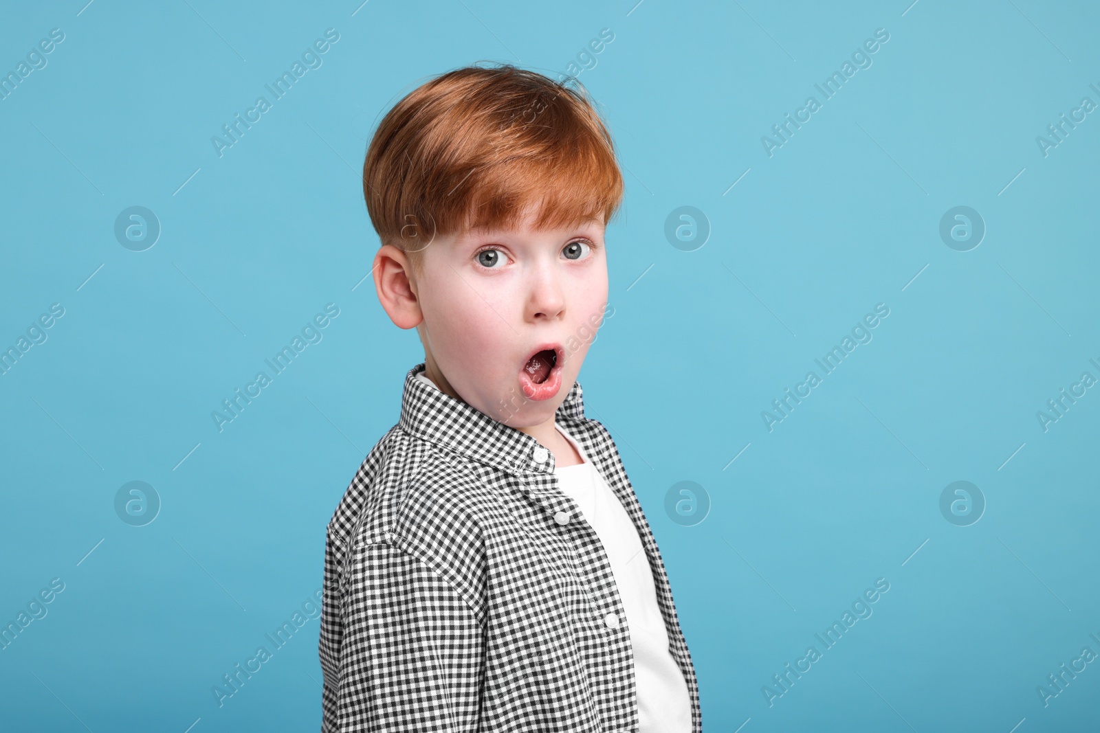 Photo of Surprised little boy on light blue background