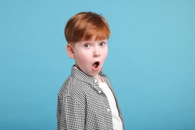 Surprised little boy on light blue background