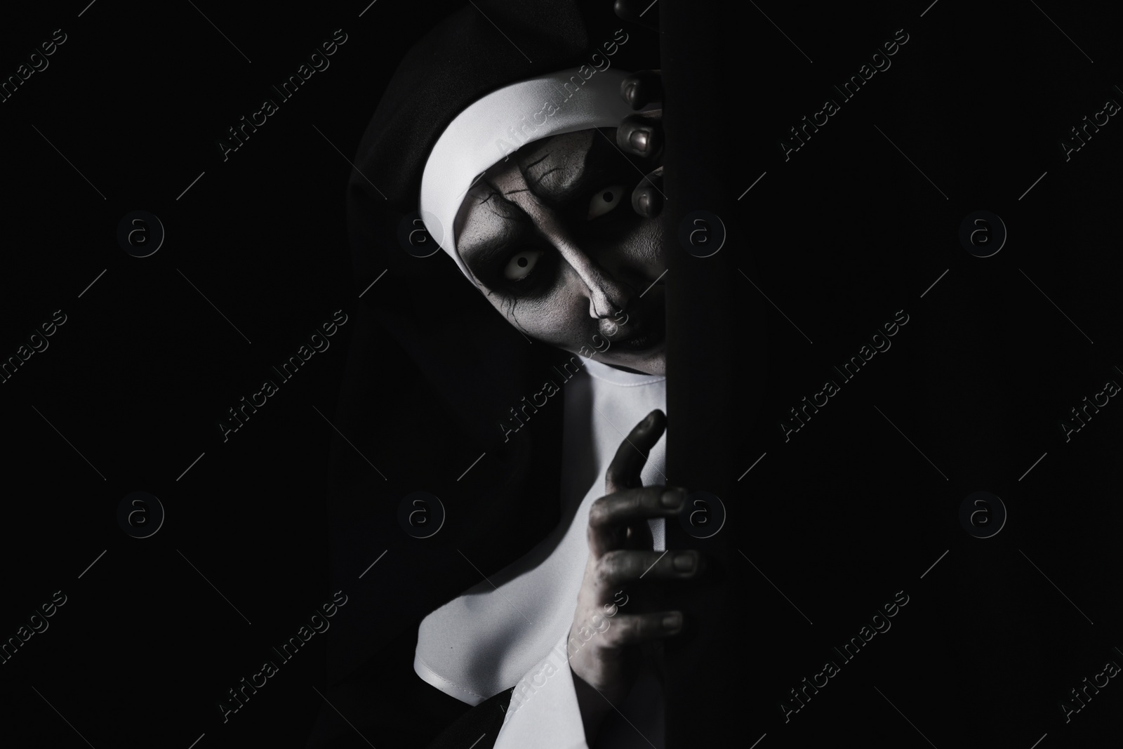 Photo of Scary devilish nun hiding on black background, space for text. Halloween party look