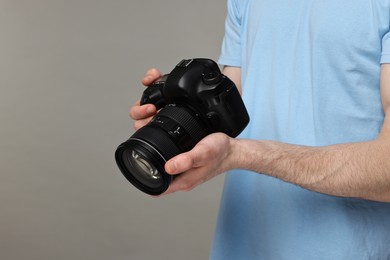 Photo of Photographer holding camera on grey background, closeup. Space for text