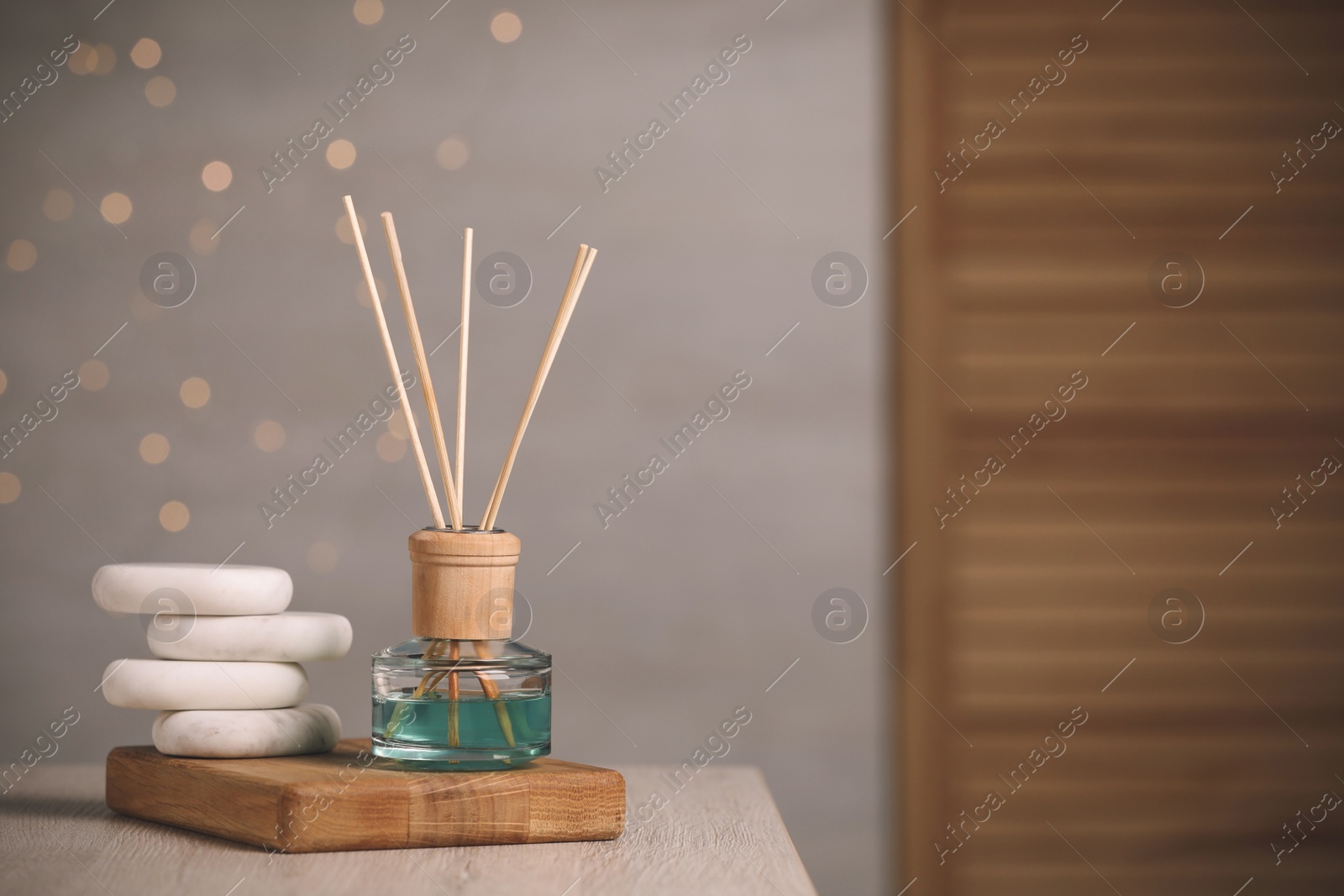 Photo of Aromatic reed air freshener and pebbles on wooden table. Space for text