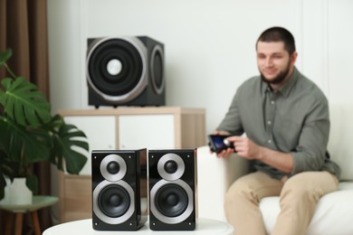 Man using remote to control modern audio speaker system in bright room