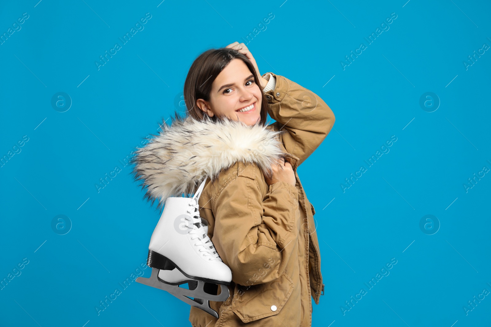 Photo of Happy woman with ice skates on light blue background