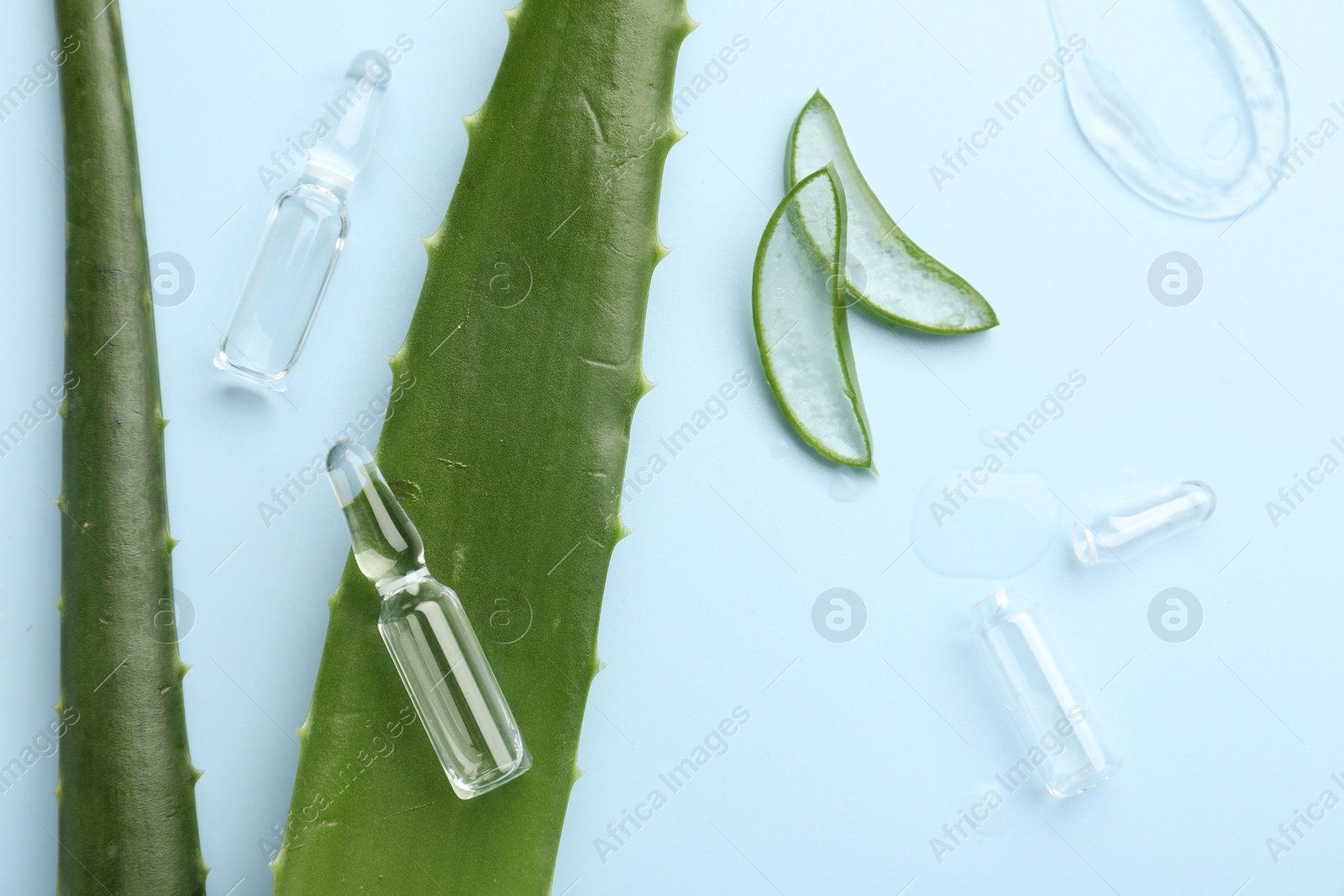 Photo of Flat lay composition with skincare ampoules and aloe leaves on light blue background