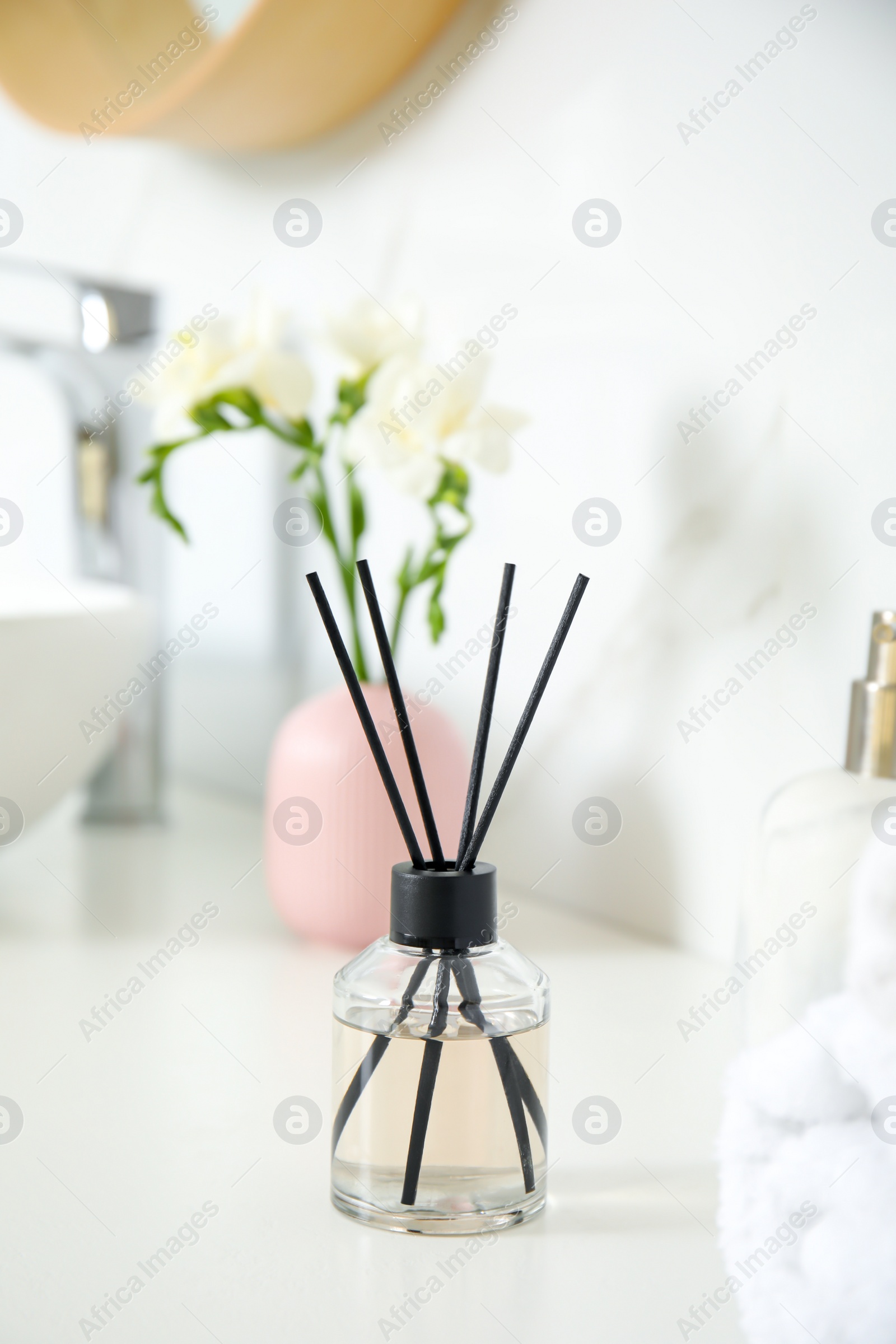 Photo of Aromatic reed air freshener on white countertop in bathroom