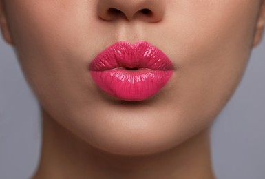 Closeup view of beautiful woman puckering lips for kiss	on grey background