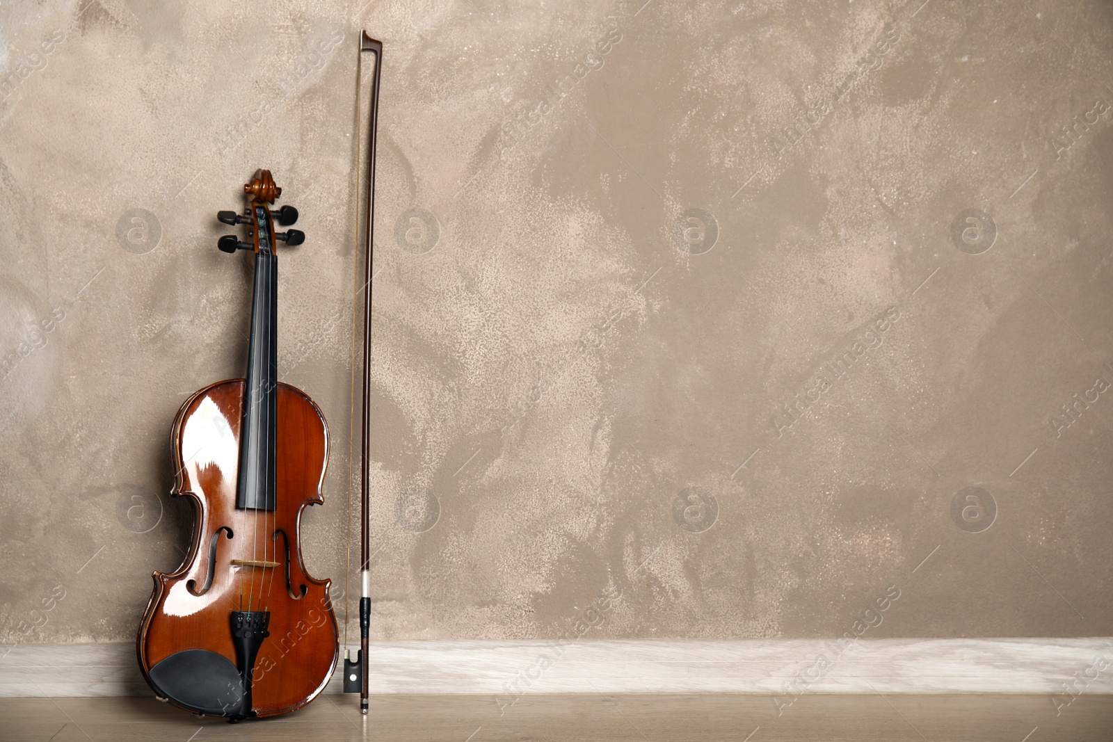 Photo of Classic violin and bow near beige wall. Space for text