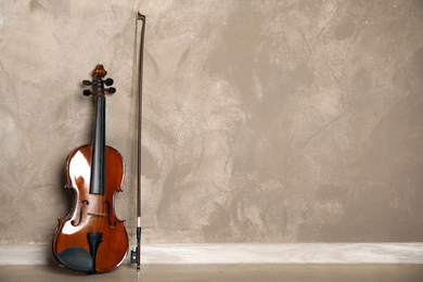 Photo of Classic violin and bow near beige wall. Space for text